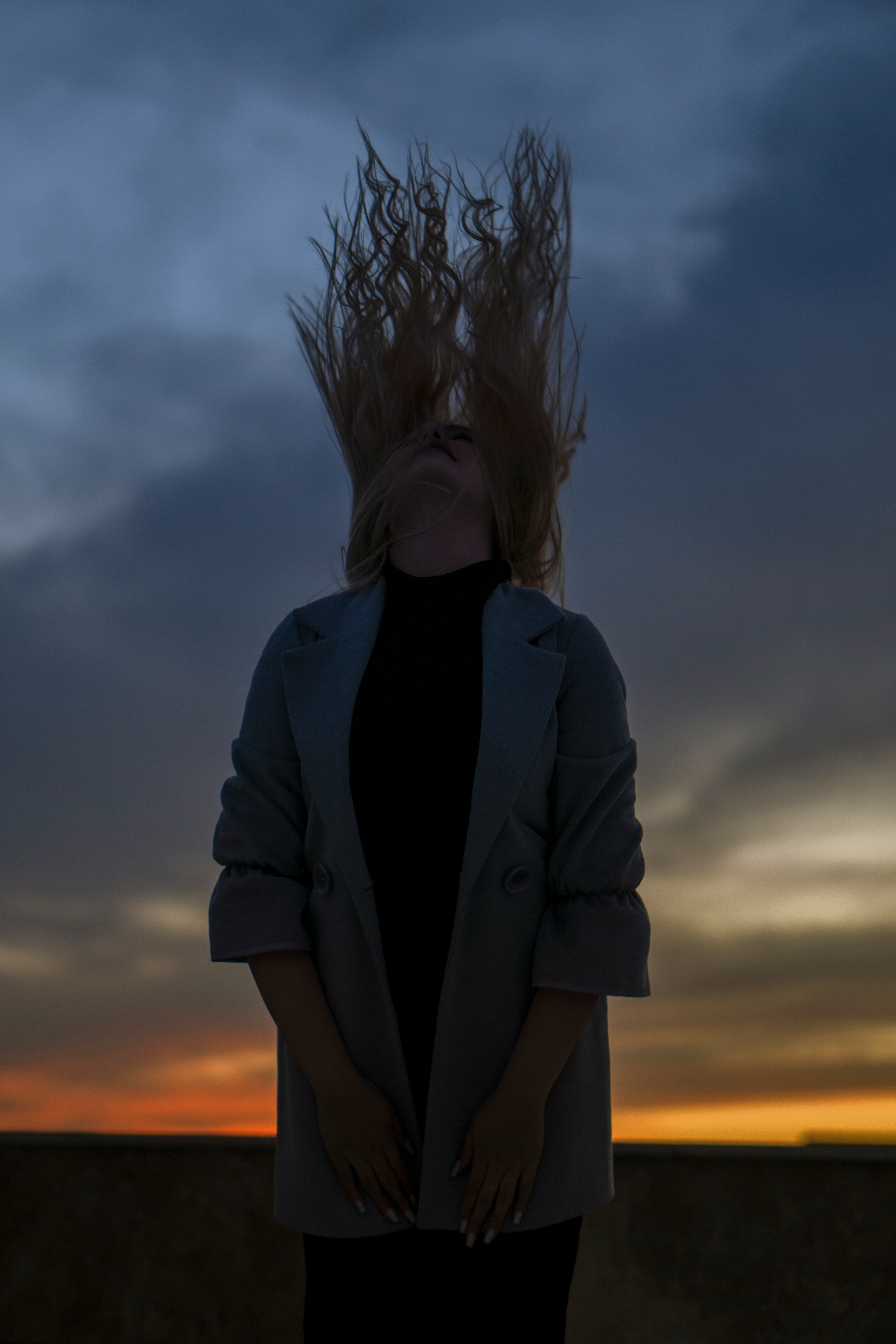 woman in black blazer standing under cloudy sky during daytime