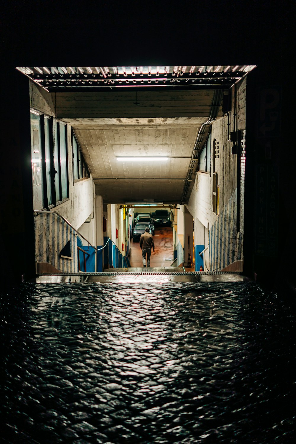 man in blue shirt standing on water between concrete building during daytime