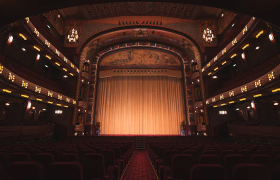 Empty theater with red seats and a gold curtain