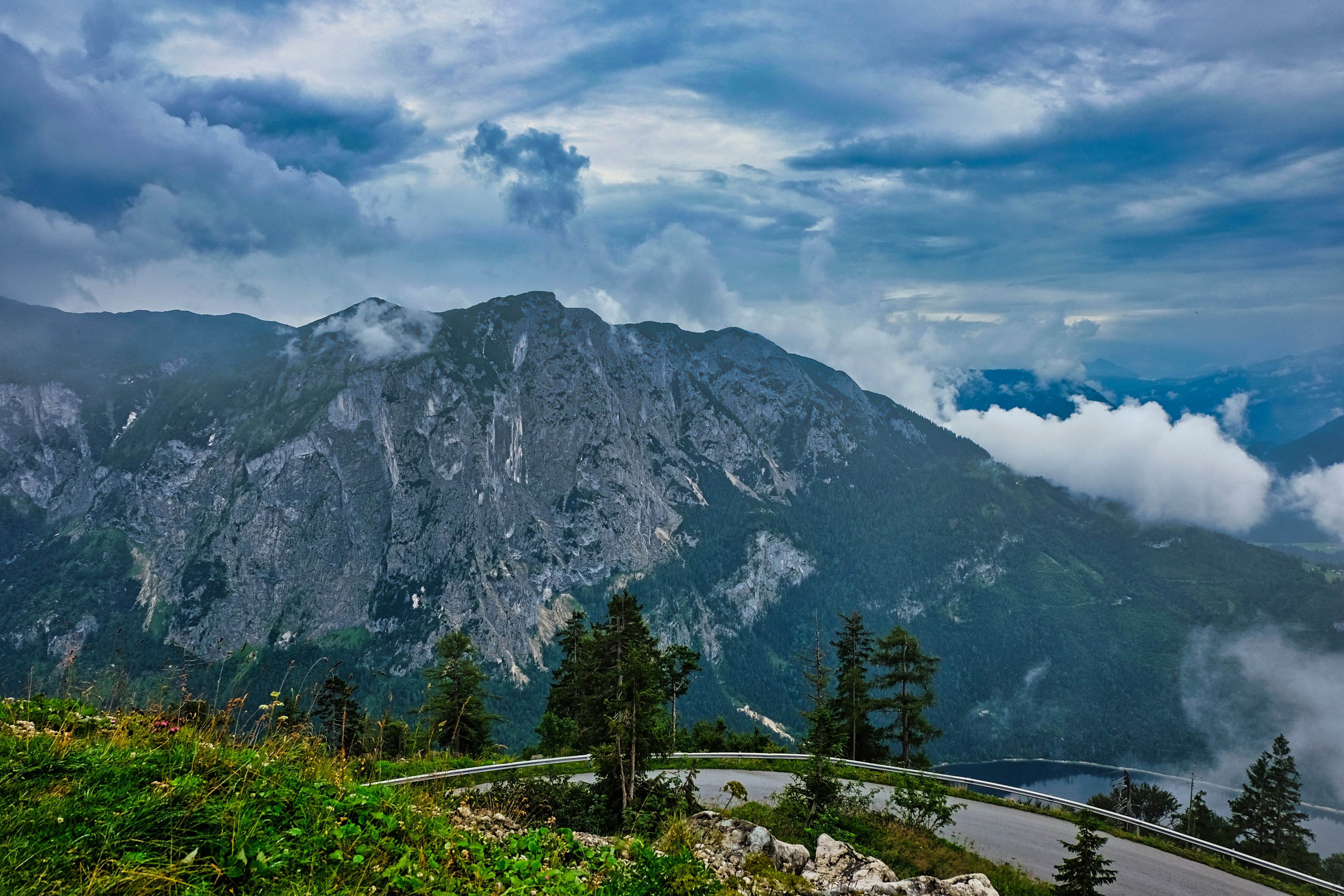 green trees near mountain under cloudy sky during daytime