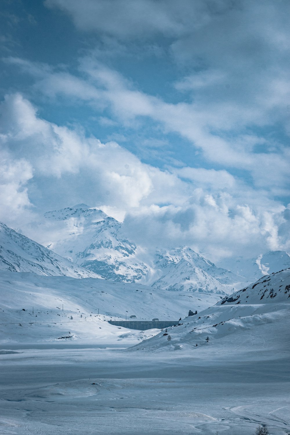 snow covered mountain under white clouds and blue sky during daytime