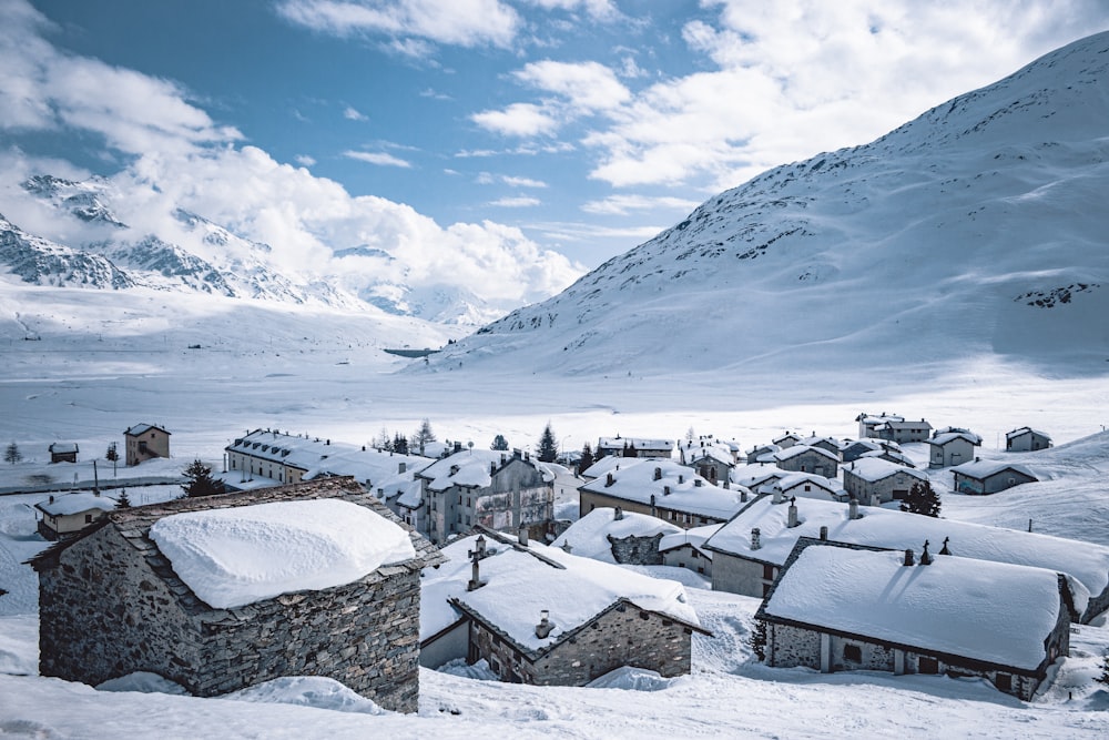 houses on snow covered ground near snow covered mountain during daytime