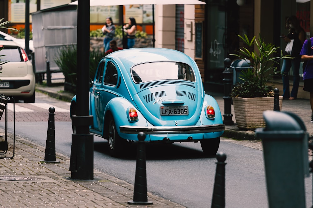 teal volkswagen beetle parked on sidewalk during daytime
