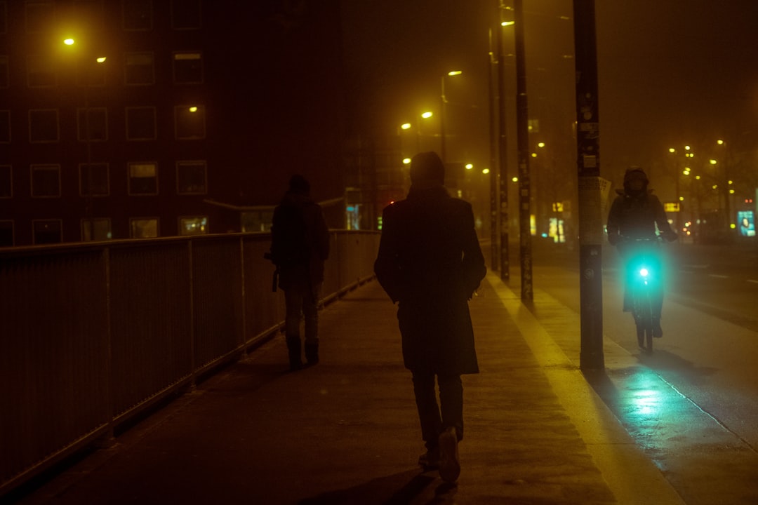 man in black coat walking on sidewalk during night time