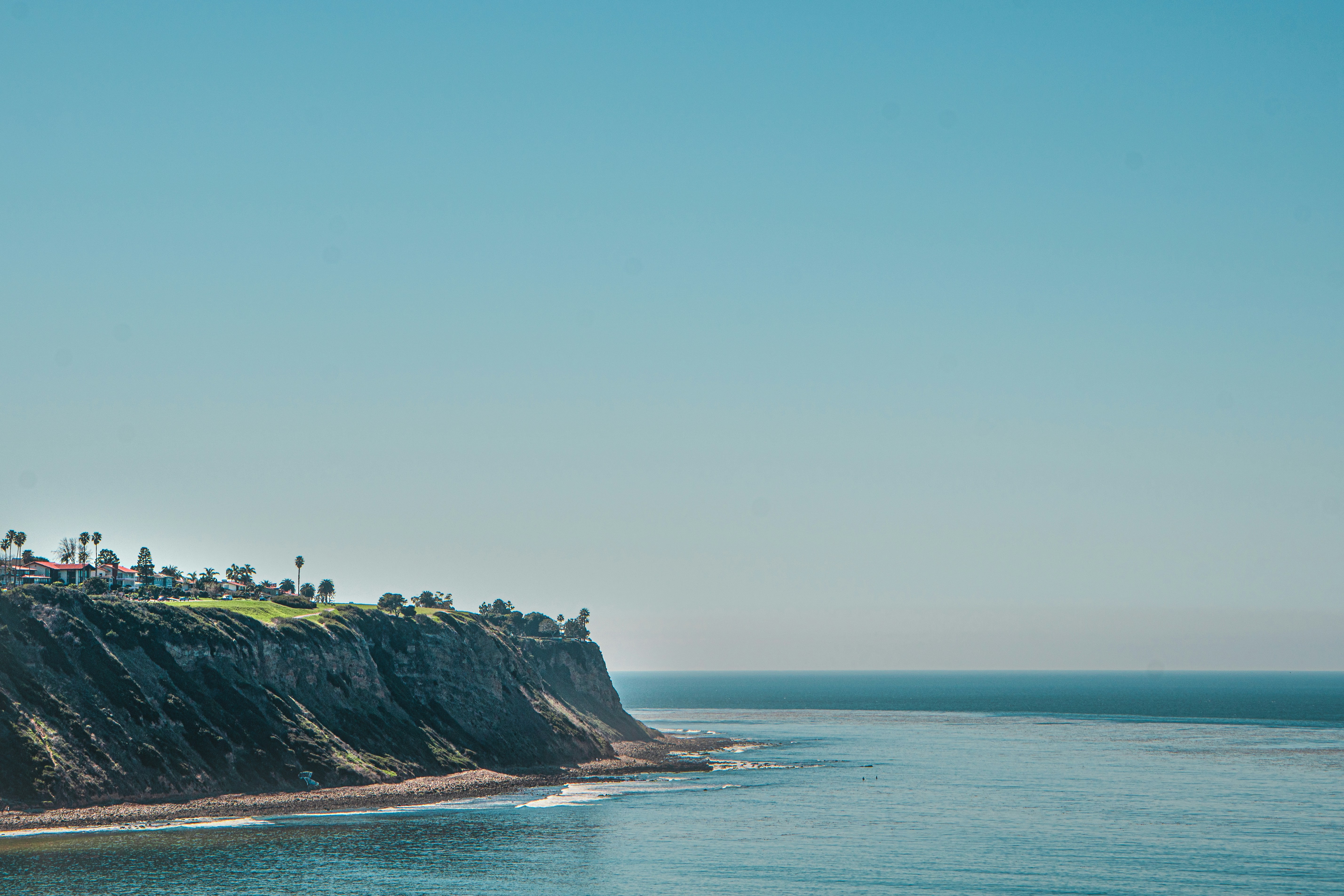 people standing on cliff by the sea during daytime