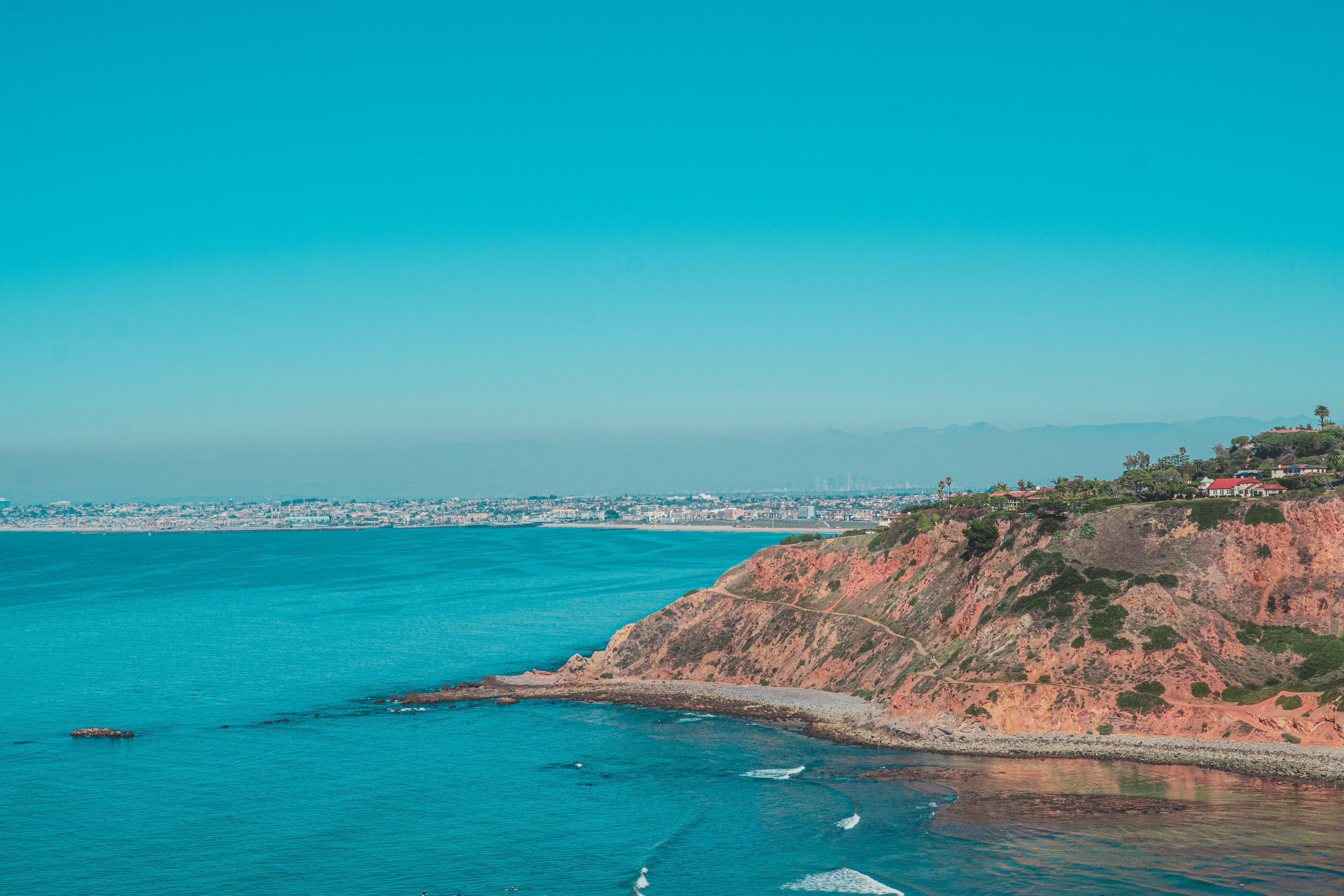 green and brown mountain beside blue sea under blue sky during daytime