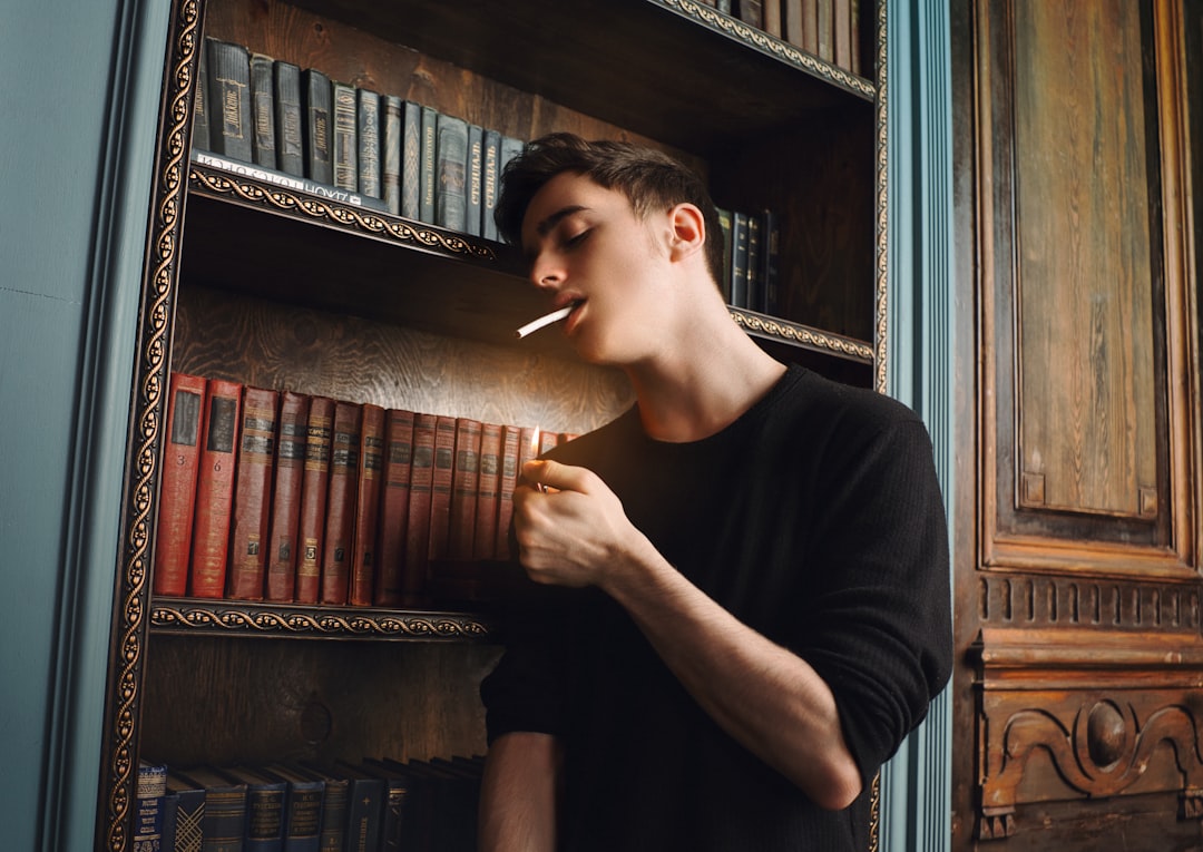 man in black crew neck t-shirt holding cigarette stick