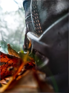 Close-up of durable hiking boots kicking up autumn leaves on a forest path.