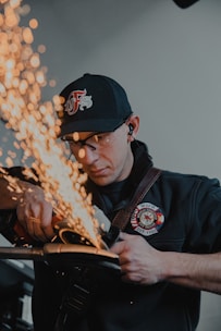 man in black and white fitted cap and black jacket holding brown wooden stick