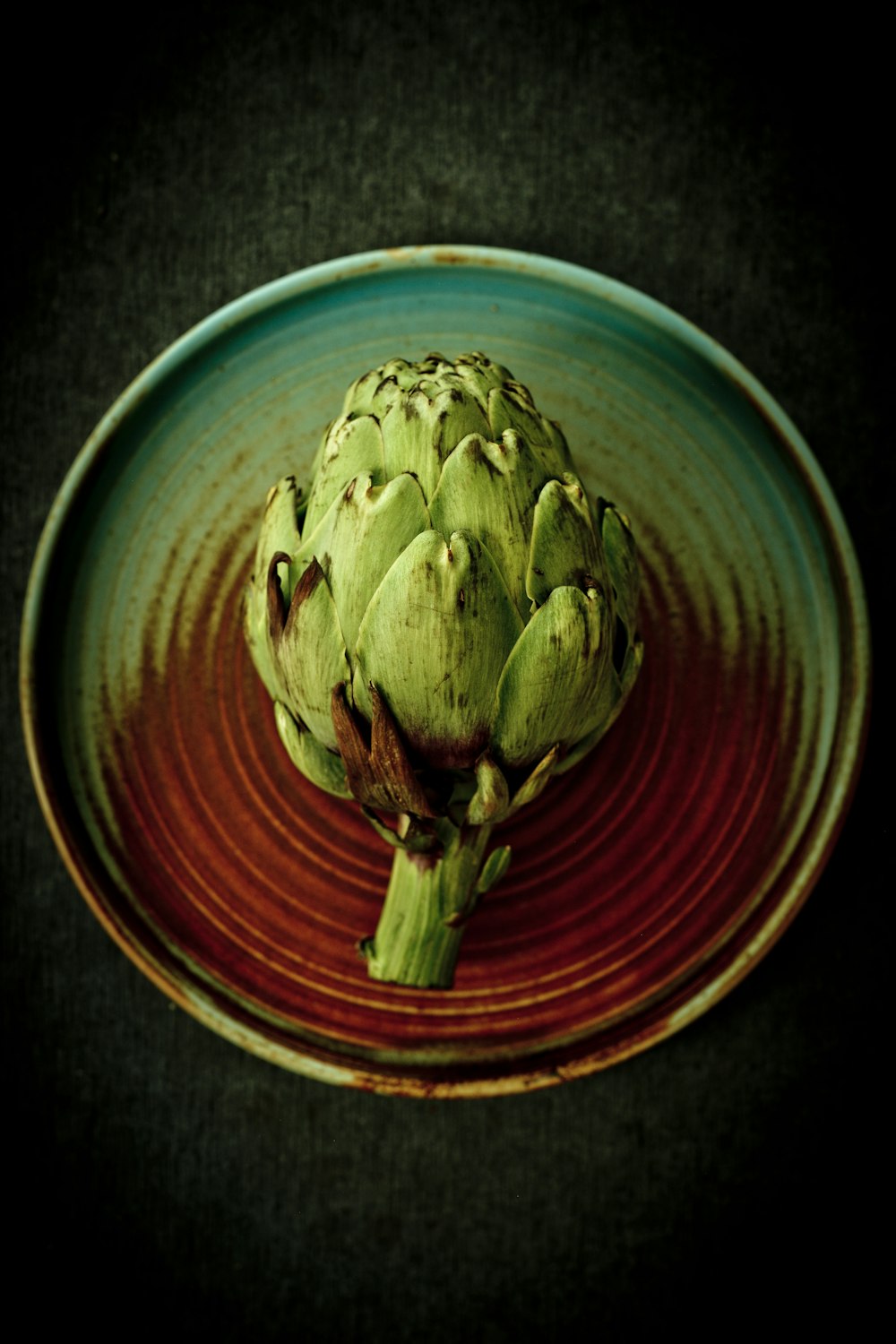 green flower bud on blue and red ceramic bowl