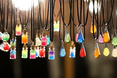 A collection of colorful borosilicate glass pendants arranged on a light wooden surface.