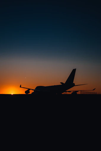 A sleek cargo plane taking off against a vibrant orange sunset, symbolizing swift global logistics.