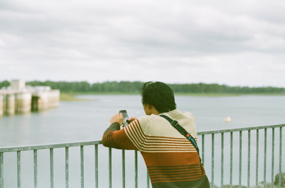 woman in brown and black stripe tank top standing on bridge during daytime