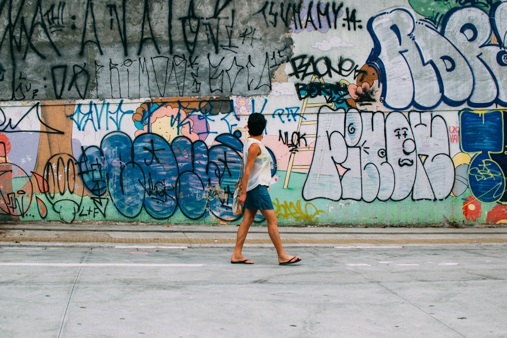 woman in white shirt and orange shorts walking on sidewalk