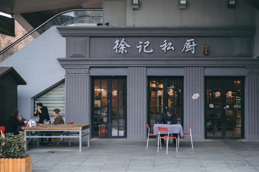 people sitting on chair in front of table near building during daytime