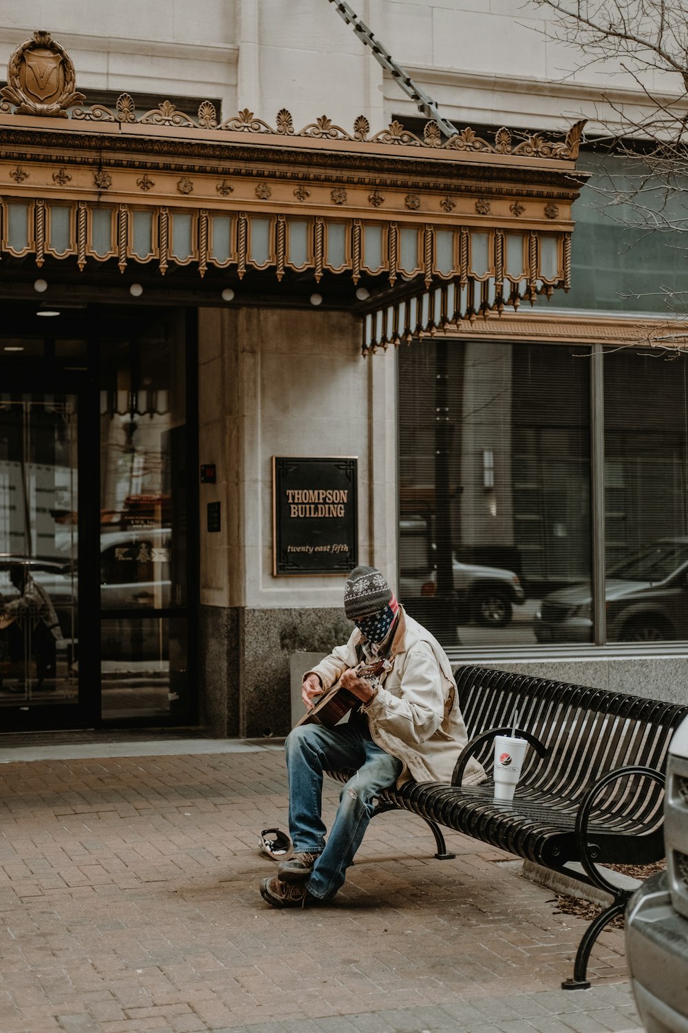 man in white and black jacket sitting on black metal bench during daytime