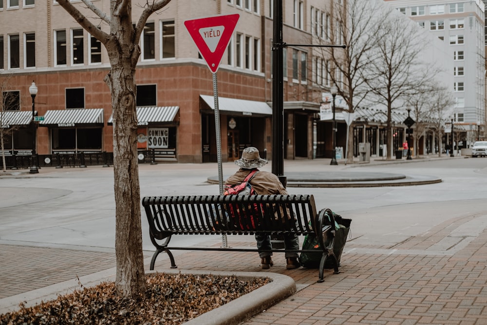 man and woman sitting on bench near road during daytime