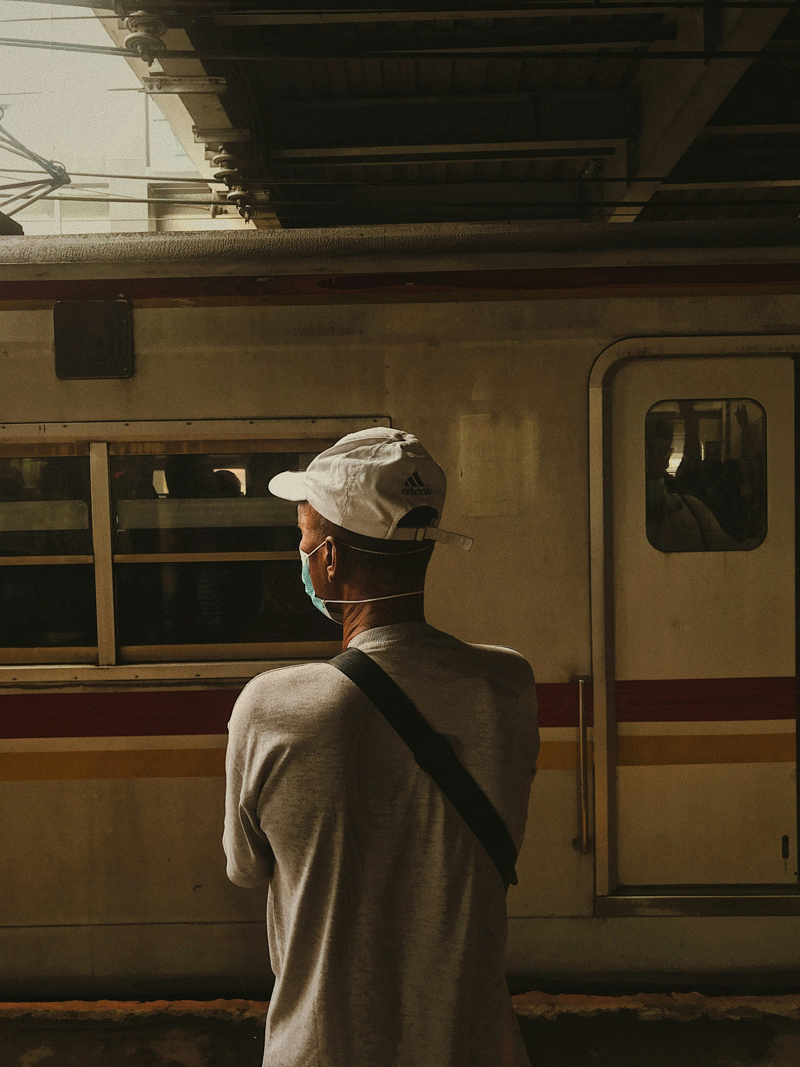 man in white shirt standing near train