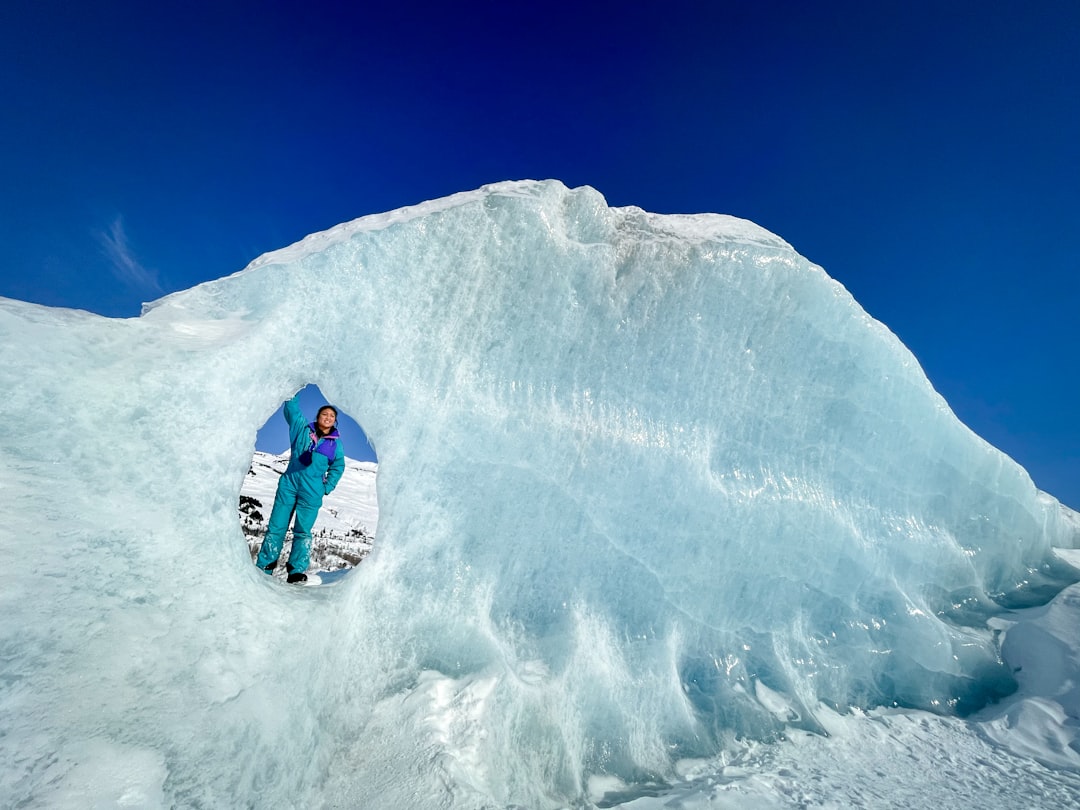 person riding blue snow mobile on snow covered mountain during daytime