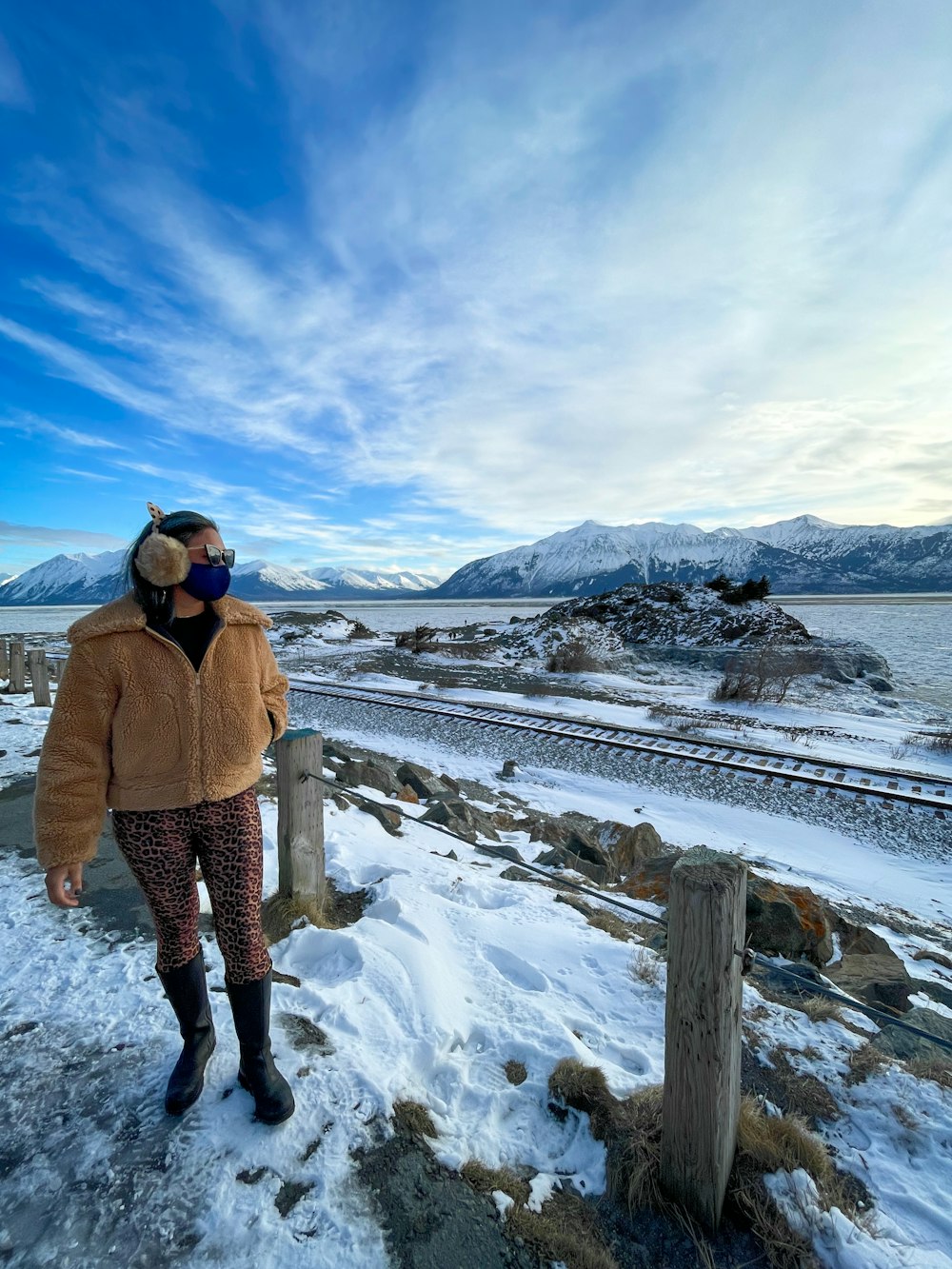 woman in brown coat standing on snow covered field during daytime