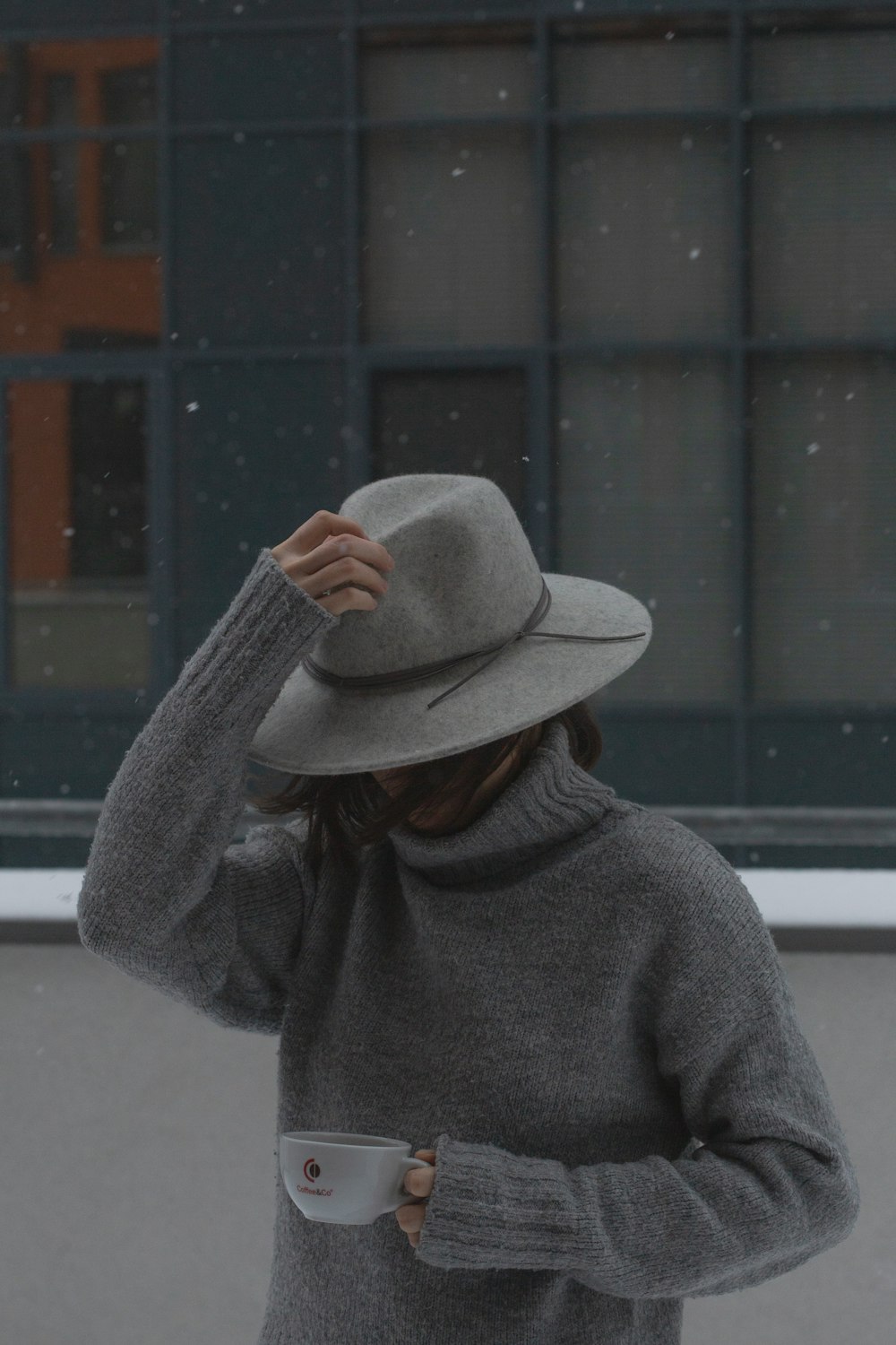 man in gray sweater wearing brown fedora hat