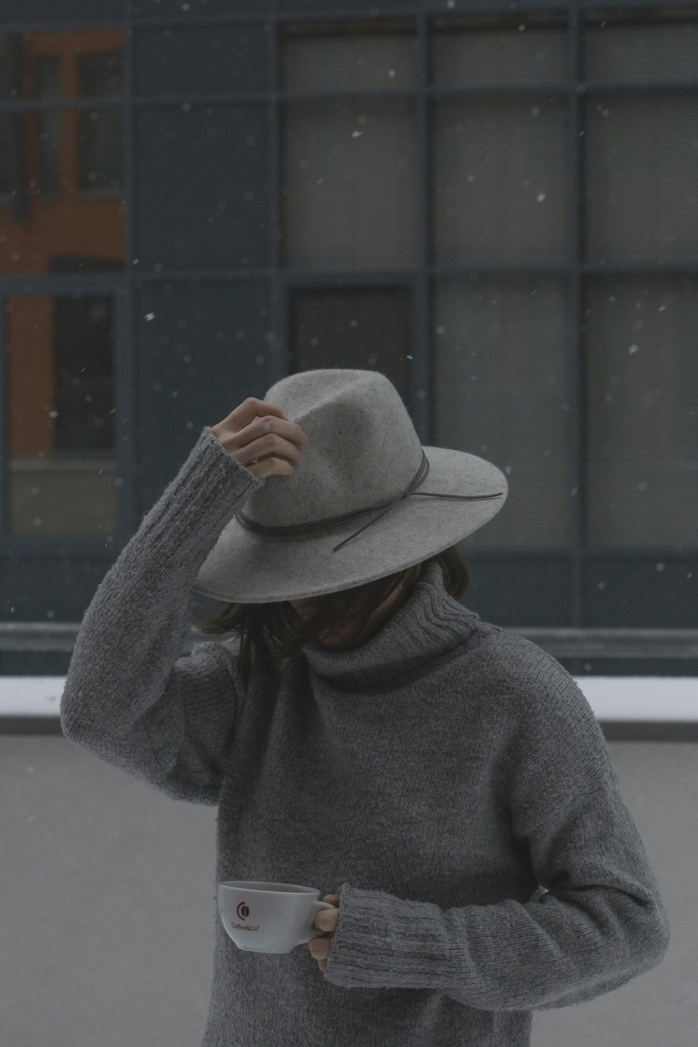 man in gray sweater wearing brown fedora hat