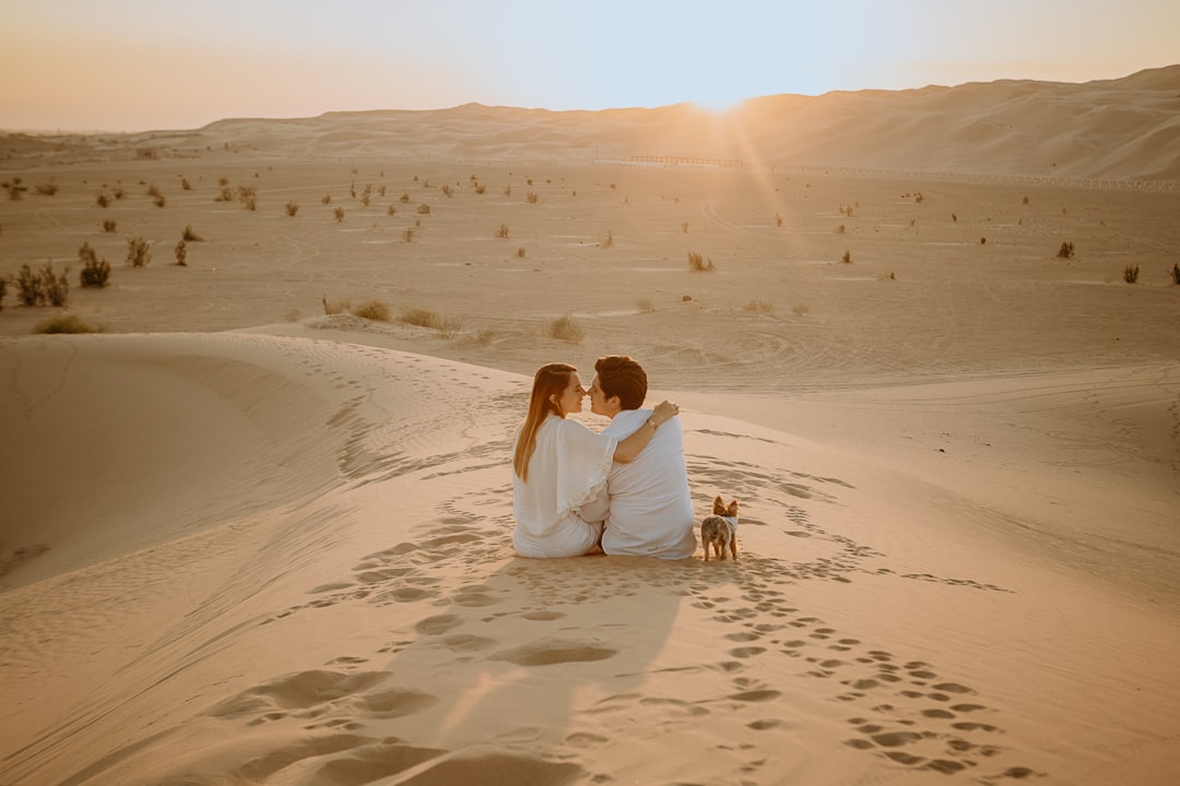 couple sitting on sand during daytime