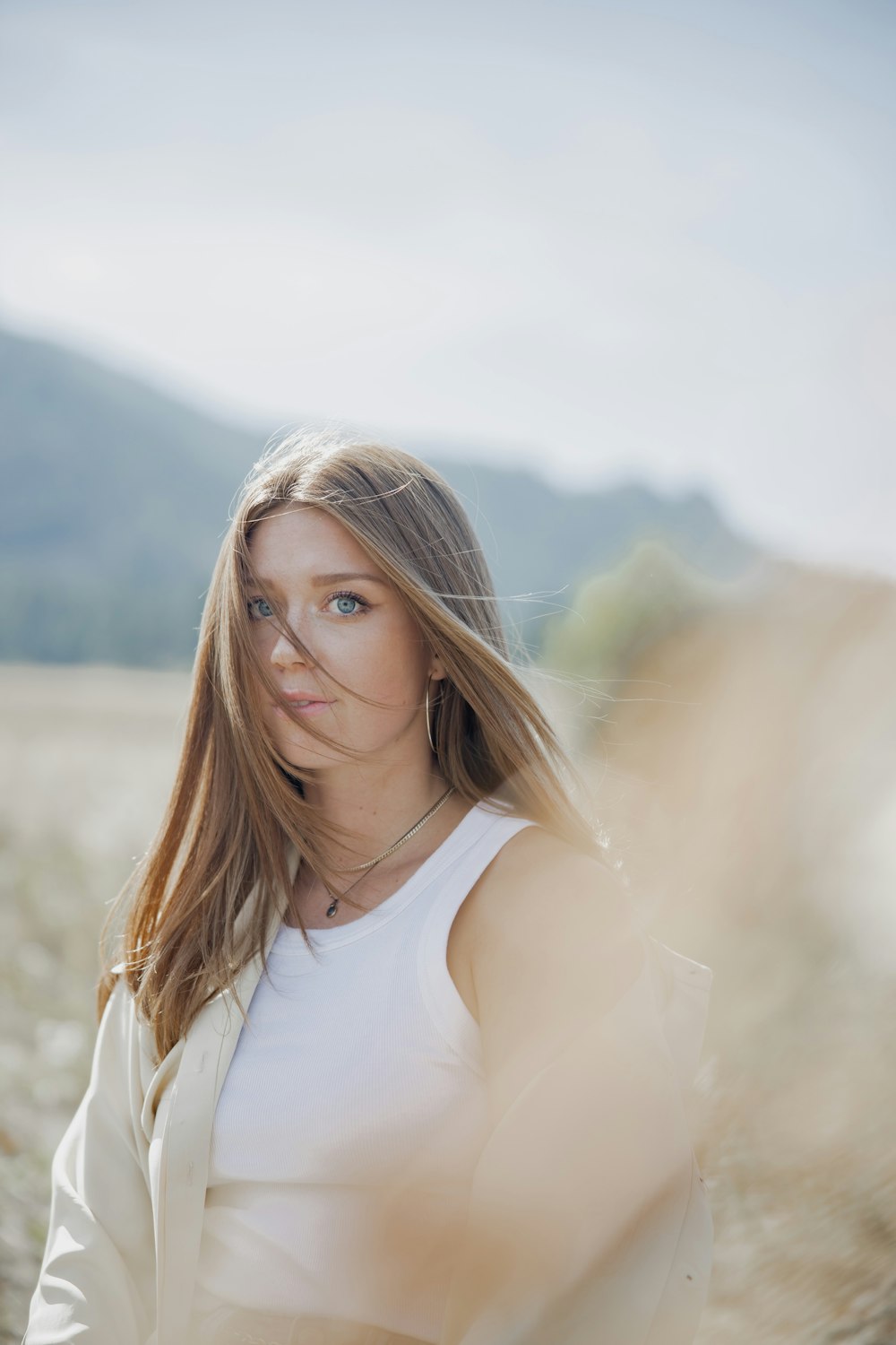 woman in white tank top standing on brown grass field during daytime