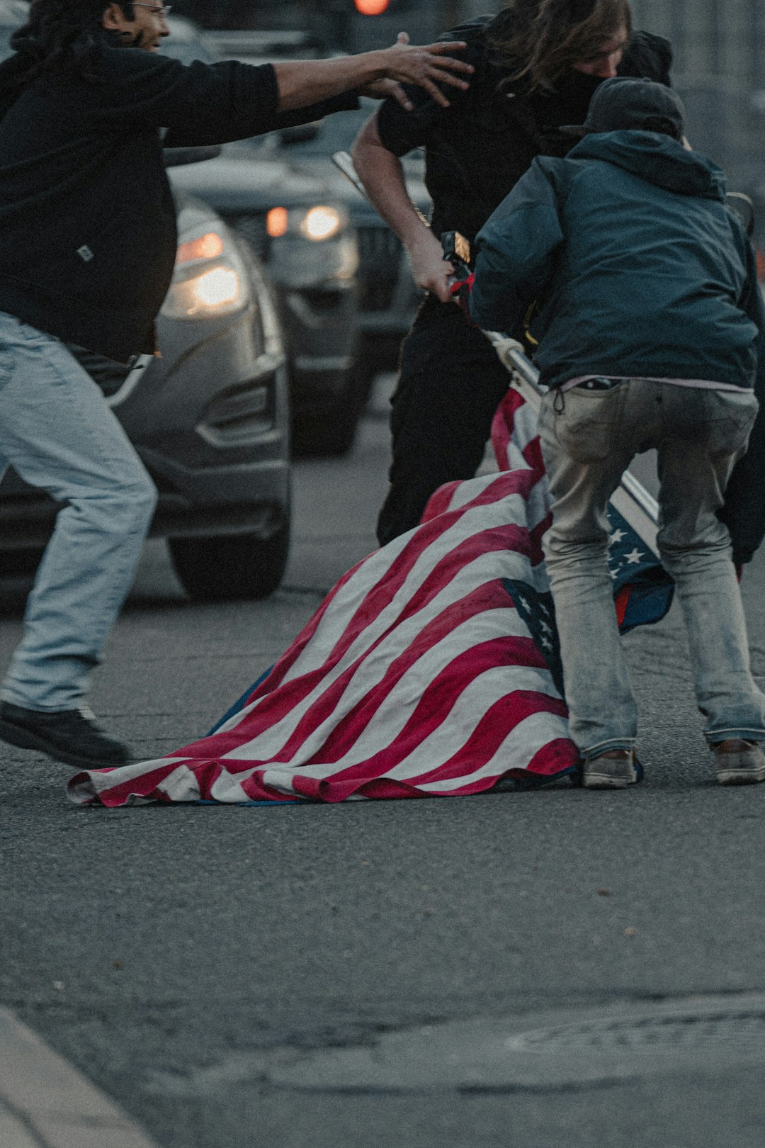 man in black jacket and blue denim jeans holding us a flag