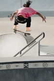 Close-up of a skateboarder performing a mid-air jump over a rail.