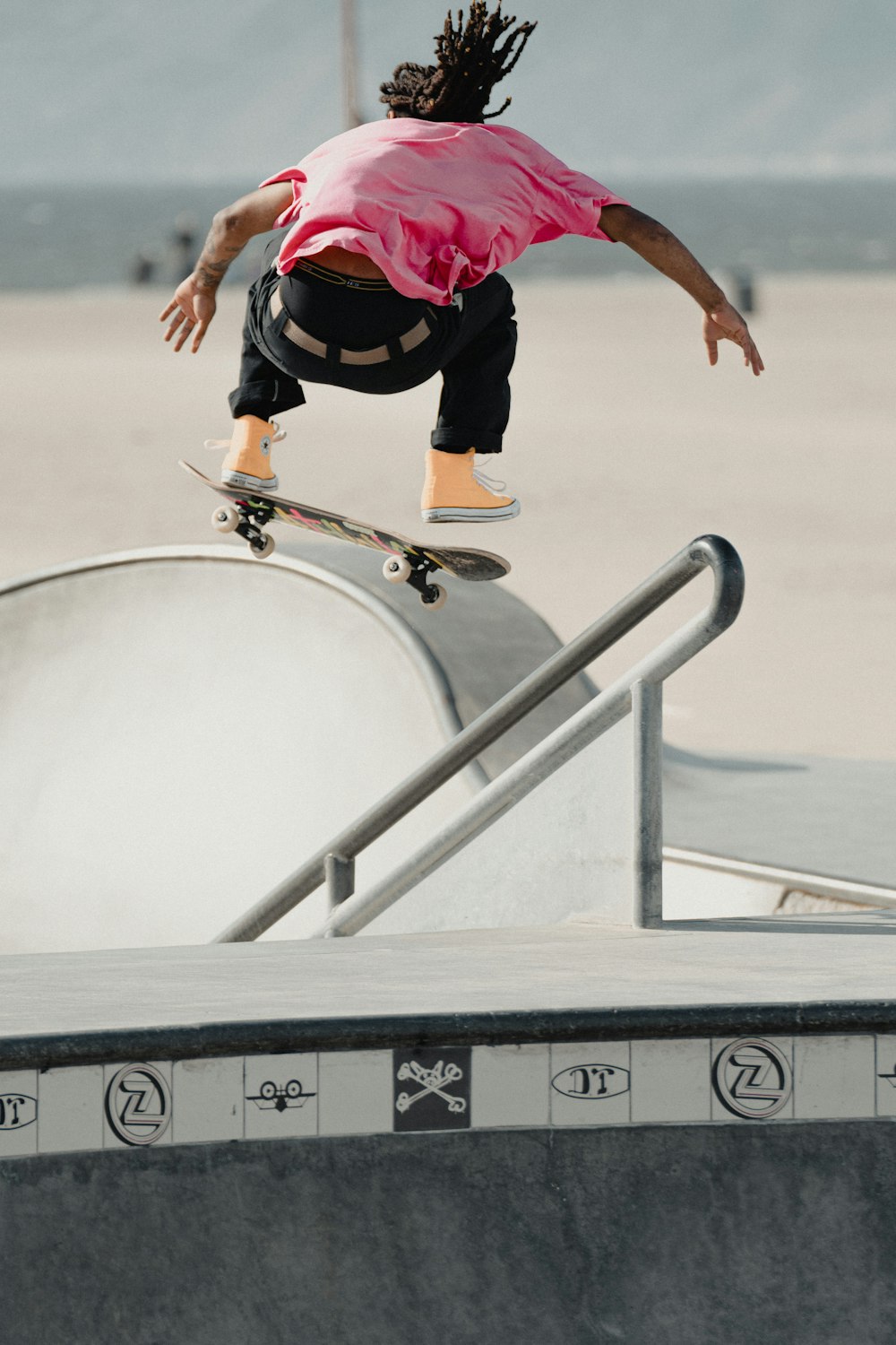 man in red and black shirt and blue shorts doing skateboard stunts