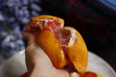 Hands holding a freshly cut grapefruit, showing its juicy interior.