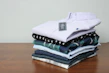 Close-up of folded t-shirts in various pastel colors on a wooden table
