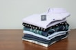 Flat lay of folded shirts and dresses on a wooden table