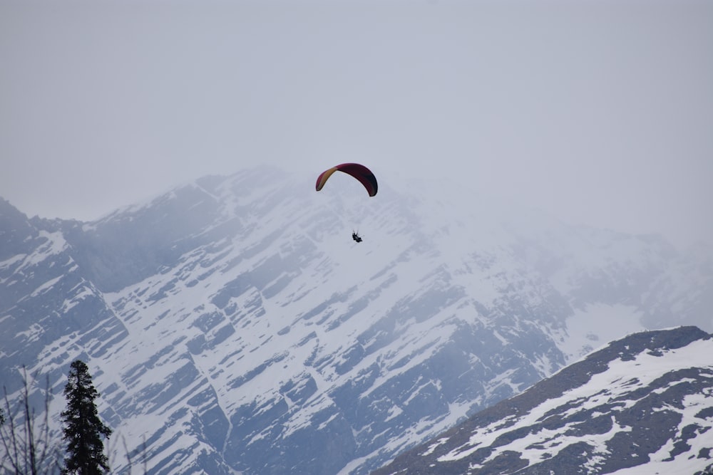 person in parachute over snow covered mountains during daytime