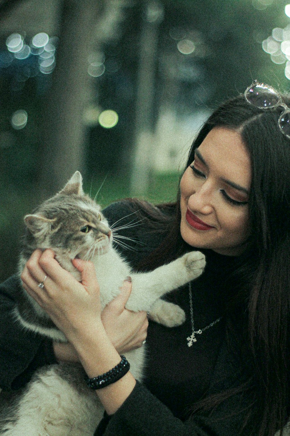 woman in black long sleeve shirt holding gray and white cat