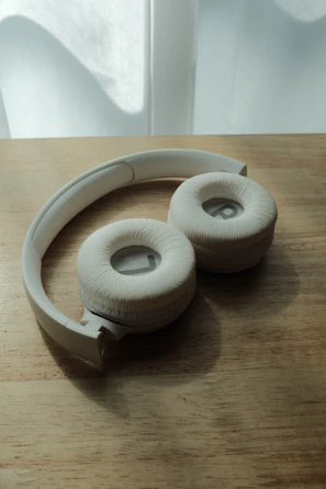 A set of trendy wireless headphones resting on a wooden table with soft natural light.