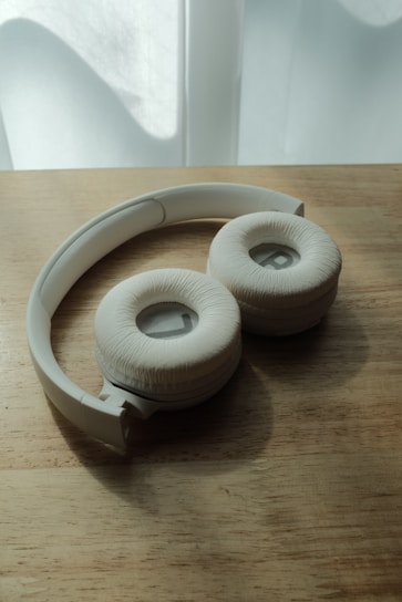 A sleek pair of over-ear headphones resting on a wooden desk with soft natural light.