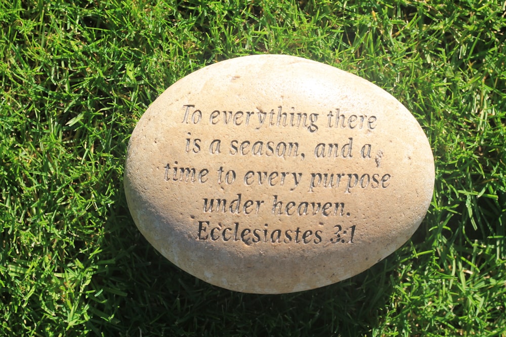 a stone with a quote on it sitting in the grass