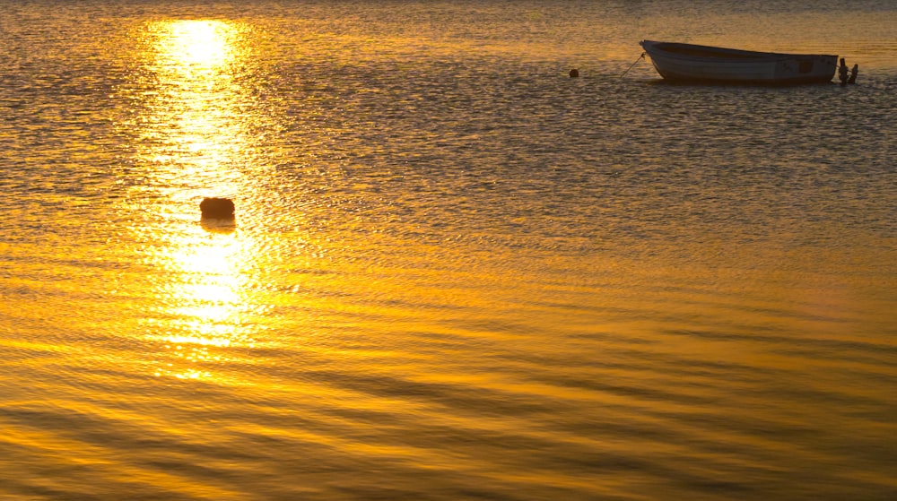 silhouette of boat on sea during sunset