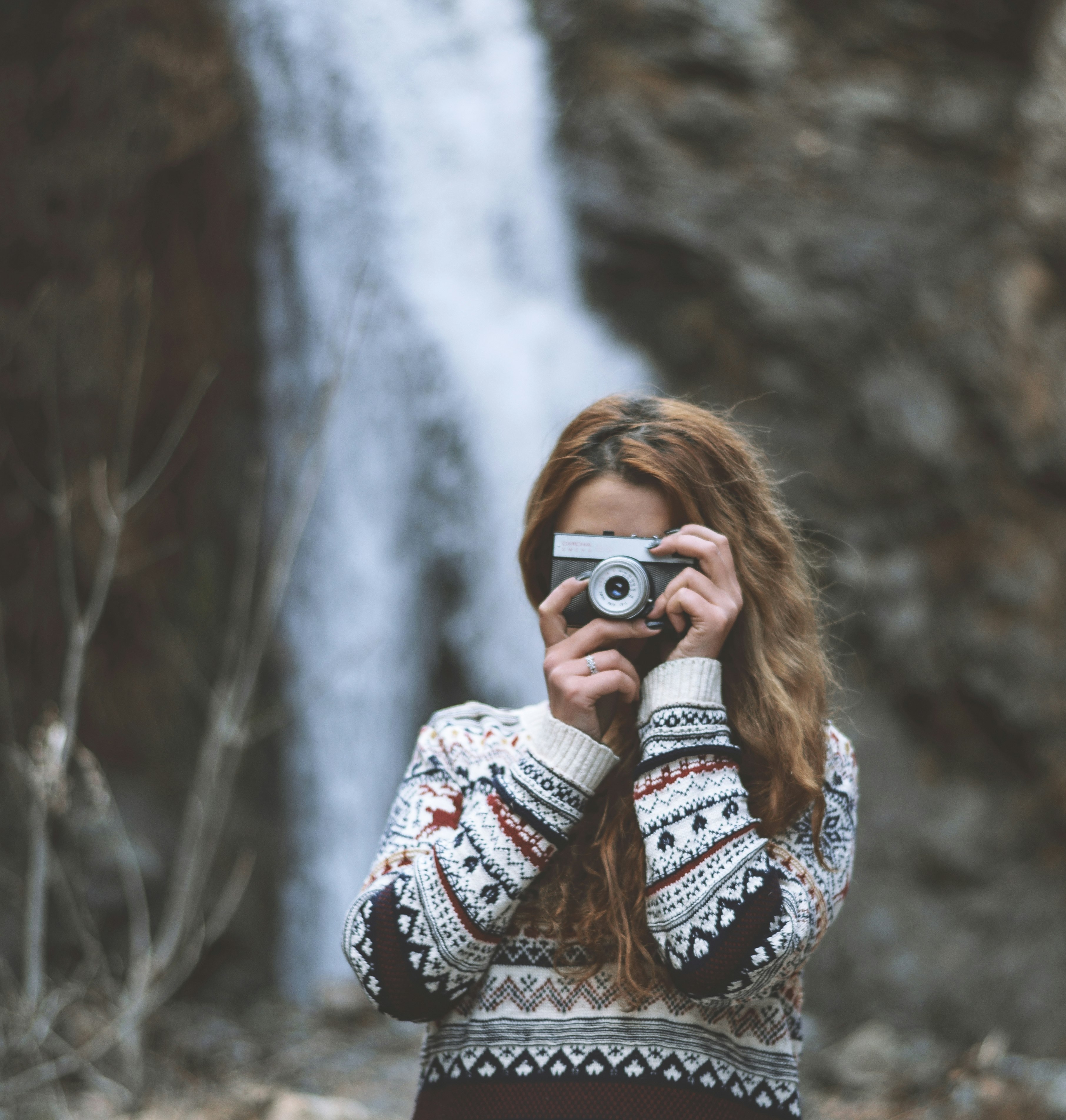 woman in black and white tribal sweater holding black and silver camera