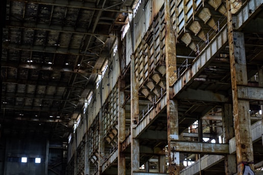 A group of urban explorers walking carefully through an abandoned industrial building with natural light streaming in.