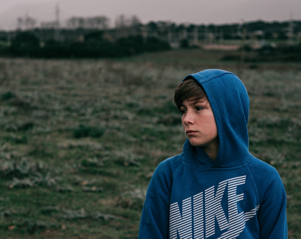 man in blue hoodie standing on green grass field during daytime