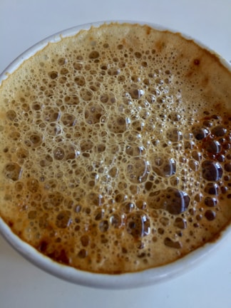 A vibrant coffee bomb fizzing as hot espresso is poured over it in a clear glass cup.