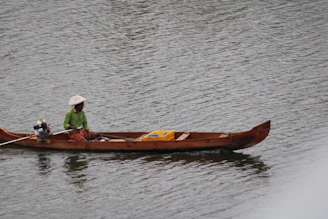 Close-up of a lanchero steering a boat with a warm smile, wearing a red and green cap reflecting the association's colors.