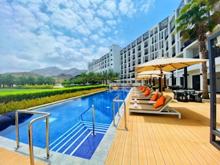 white and brown wooden lounge chairs near swimming pool during daytime
