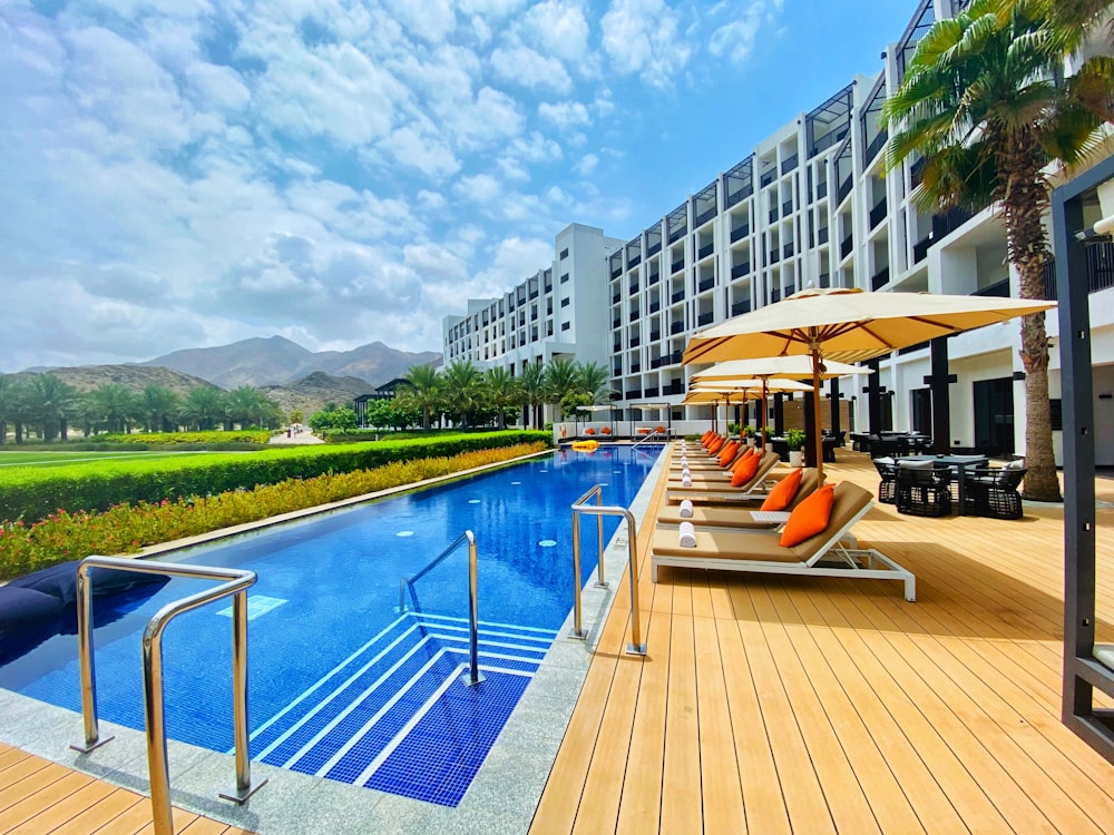 white and brown wooden lounge chairs near swimming pool during daytime