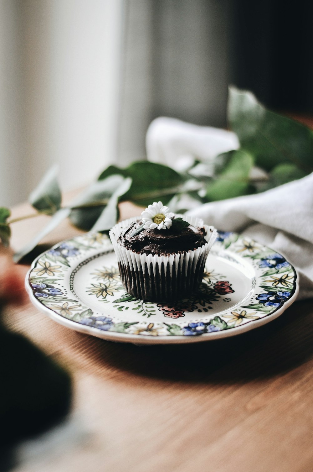 black cupcake on white and blue floral ceramic plate