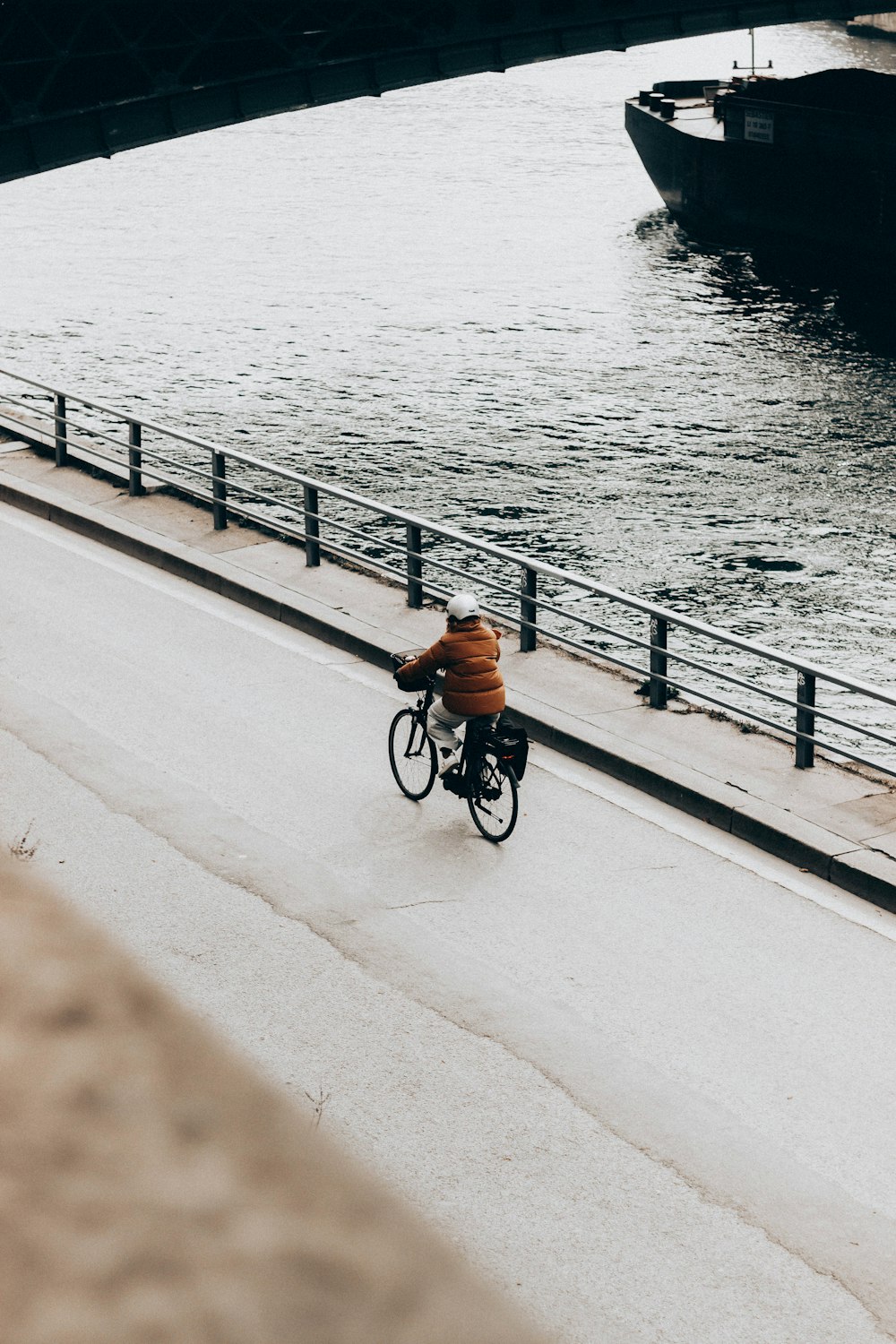 homme en chemise orange faisant du vélo sur le pont pendant la journée