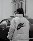 woman in white and black adidas hoodie standing near black car